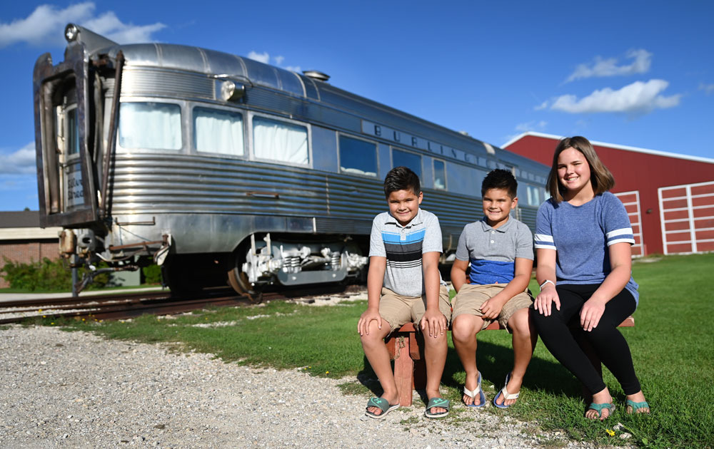 Children sitting in front of a railroad car
