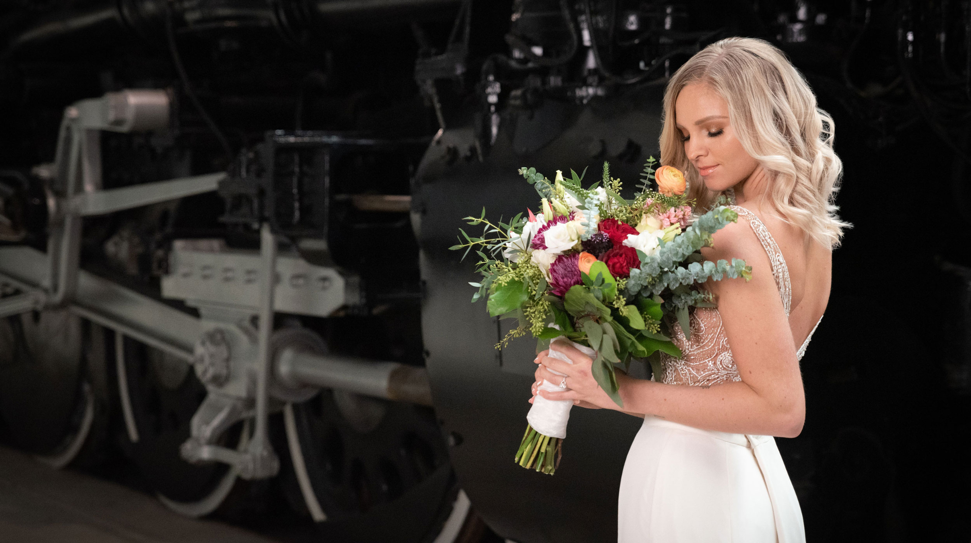 women holding flowers wearing a wedding dress in front of the side of a train