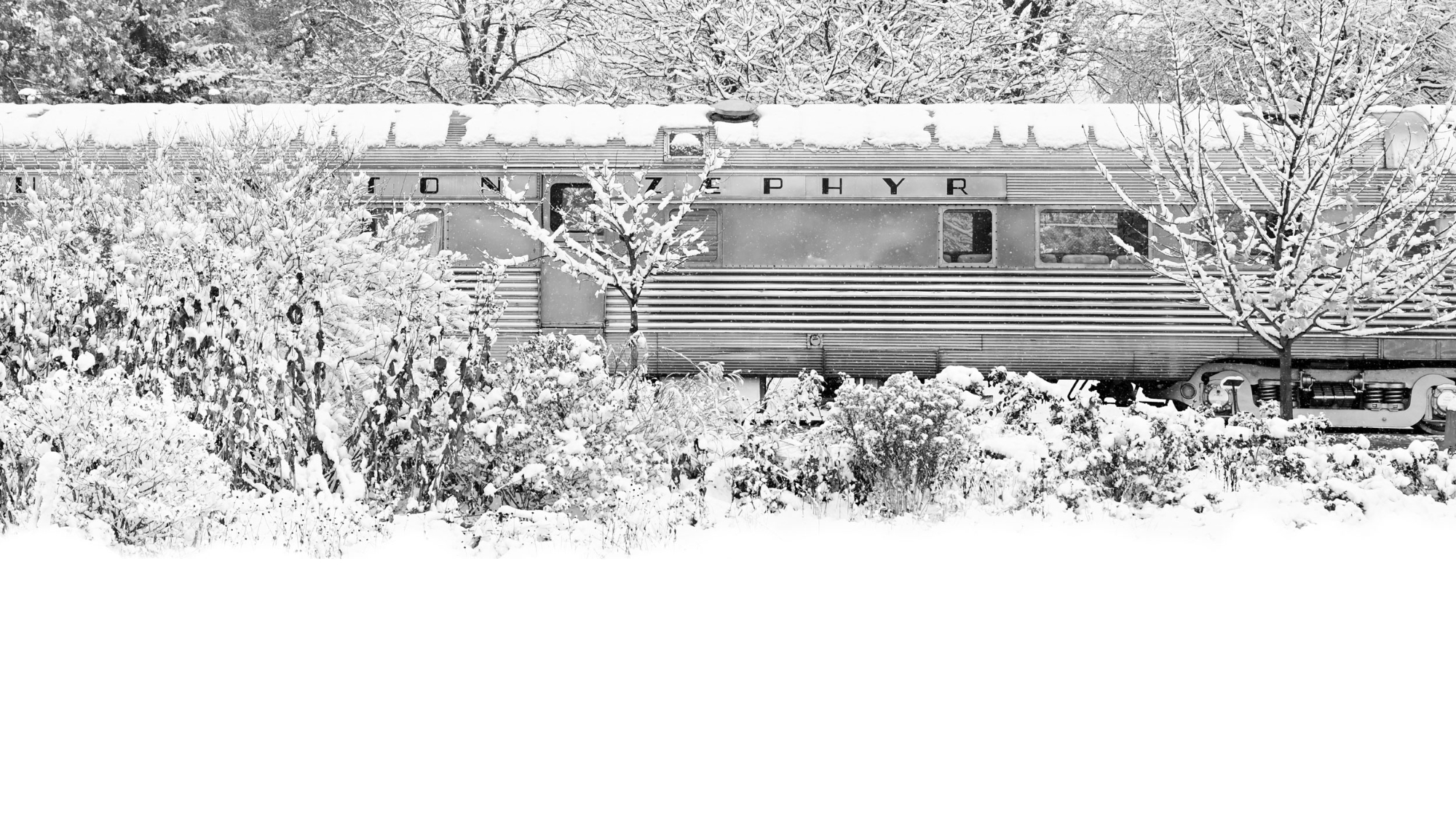 a train car on train tracks in winter partially hidden behind trees